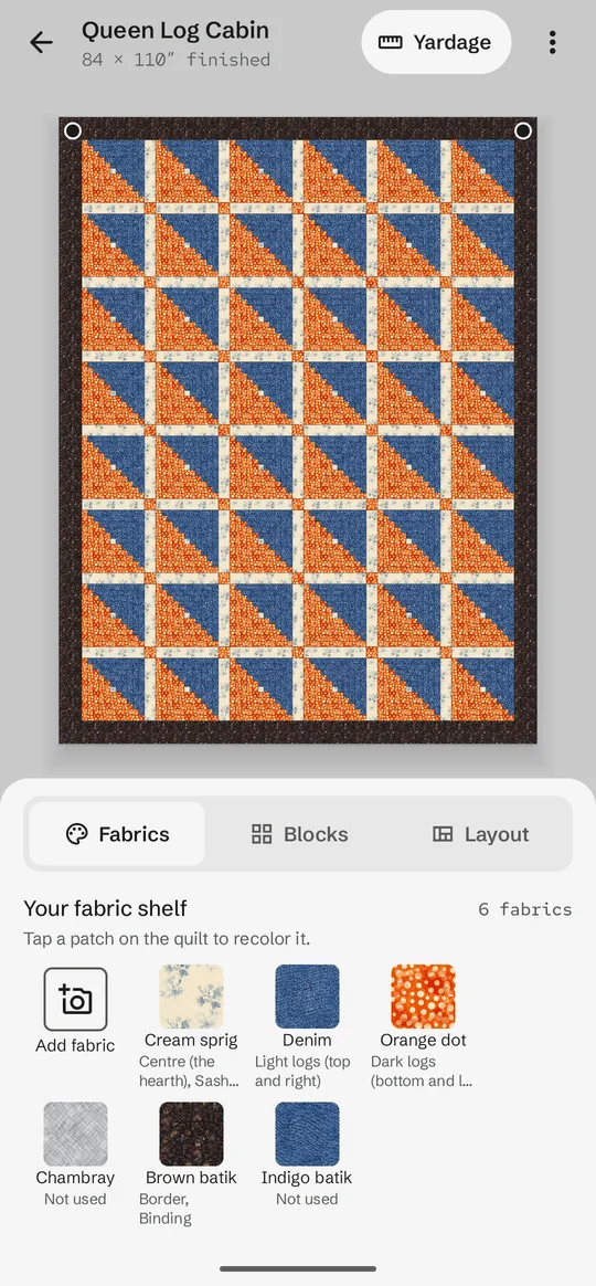 A queen-size Log Cabin quilt on Sashing's design wall, drawn in photographed denim, orange dot, cream and brown batik fabrics, with the fabric shelf below